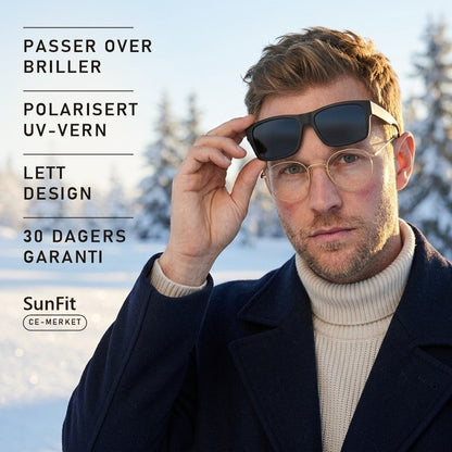 Mann med briller løfter SunFit fit-over-solbriller i vintersol over snø